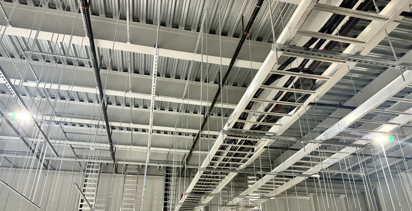 Cable tray and conduit runs under the deck in a plant hall before the ceiling closes