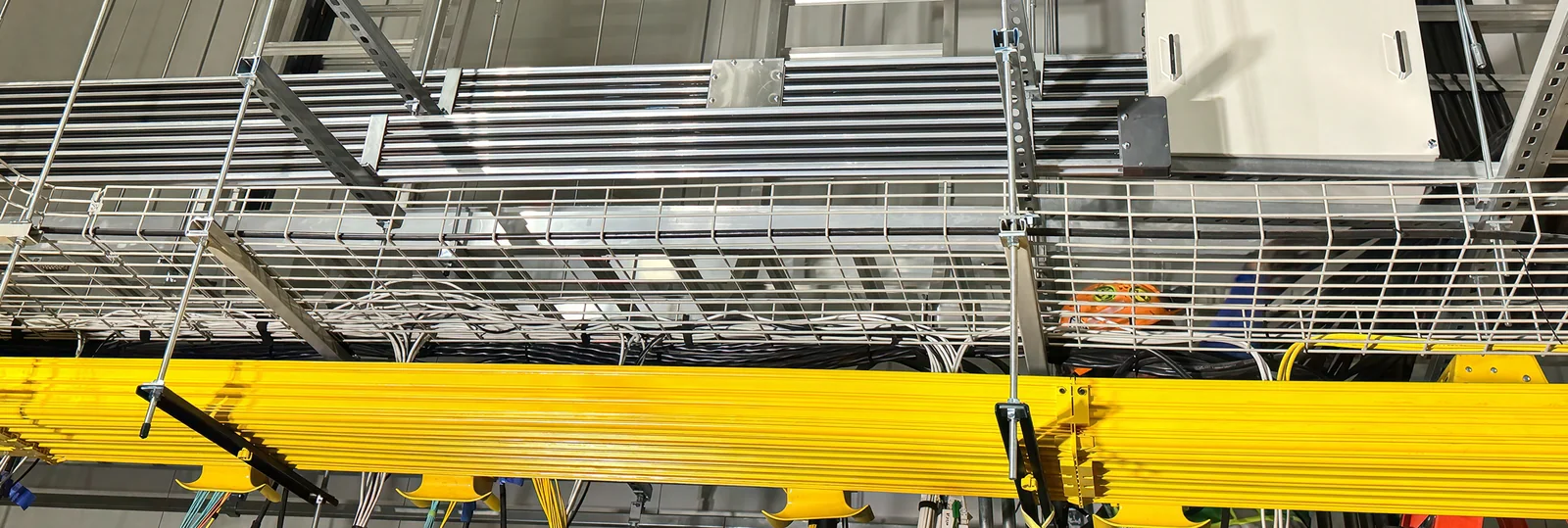 Conduit banks, basket tray and fiber raceway above a plant floor